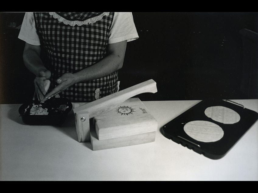 Black and white image of a woman making tortillas.